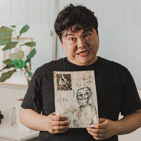 不可解な絵を持ち強張った顔でこちらを見る人物の写真