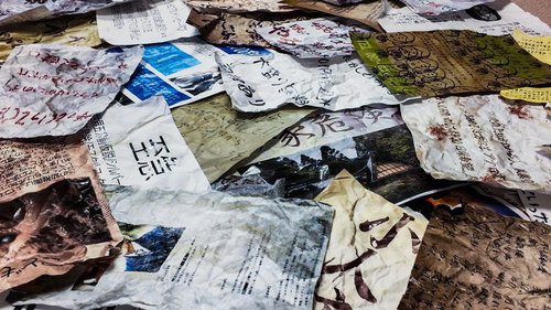 床に散乱する手書き文字と写真の怪文書群