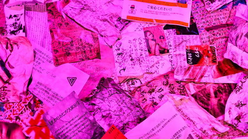 ピンクの照明に照らされた手書き文書や怪文書が散乱した光景の写真