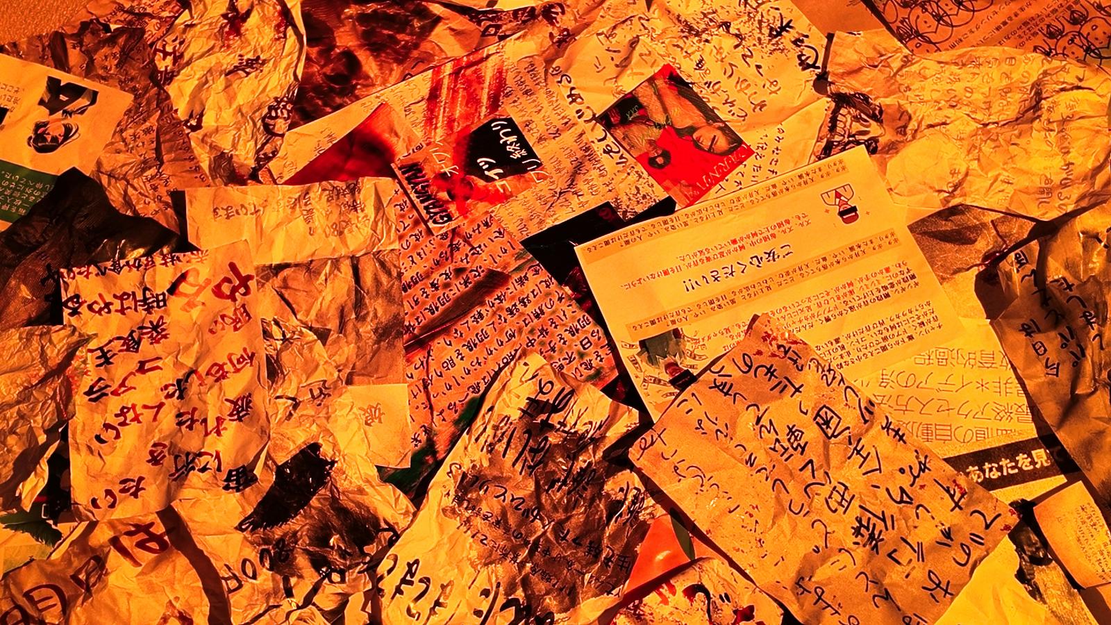 オレンジ色の照明で照らされた大量の手書き文書が散乱している