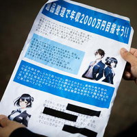 年収2000万円を謳う怪しい勧誘チラシを両手で持つ人物の写真