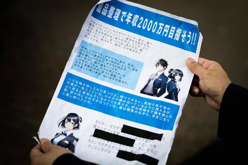 年収2000万円を謳う怪しい勧誘チラシを両手で持つ人物