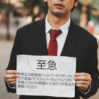 至急と書かれた怪文書を持つ黒いスーツの男性の写真