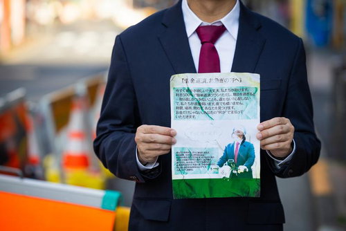 怪しい借金返済チラシを掲げるスーツの男性