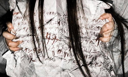意味不明な文字が書かれた怪文書を握りしめる長髪女性の手元