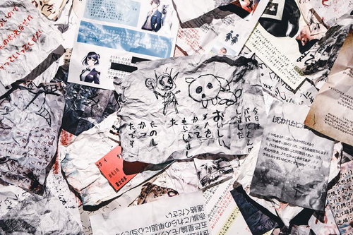 手書き文字とイラストが重なり合う怪文書の束