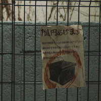 金網フェンスに貼られた手書きの「箱円あげます」怪文書の写真