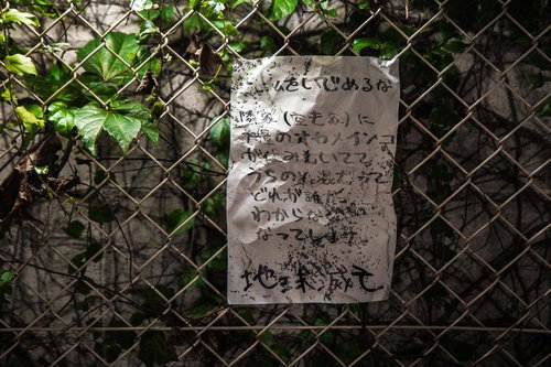 金網フェンスに貼られた汚れた手書きの怪文書