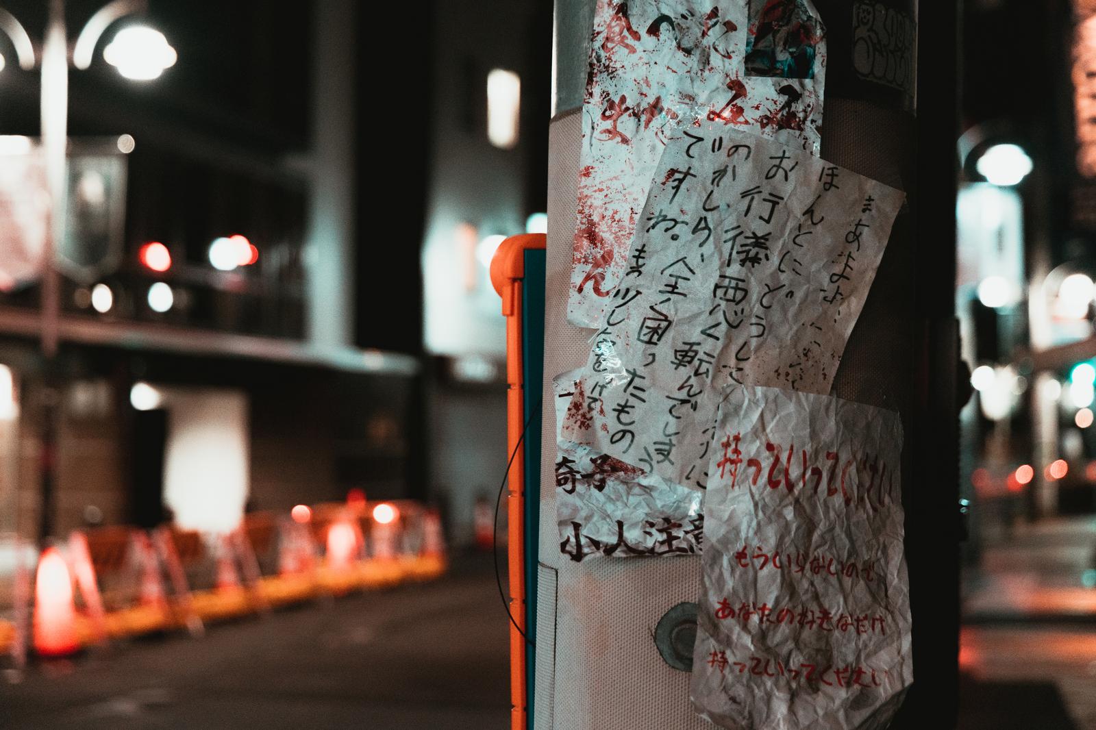 夜の街の電柱に貼られた手書きの怪文書のような複数の貼り紙