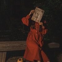 暗闇のベンチで怪文書を読む赤いワンピース姿の女性の写真