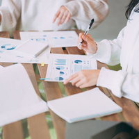 デスクの上でグラフ資料を確認する会議の様子の写真