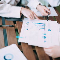 資料のグラフを確認しながら打ち合わせをする様子の写真