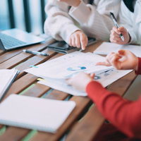 グラフ資料を元に打ち合わせする複数人の手元の写真