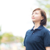 紺色の制服を着たヘルパーの女性が屋外で空を見上げるの写真