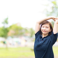 公園で両手を上げて伸びをする女性のリフレッシュの写真