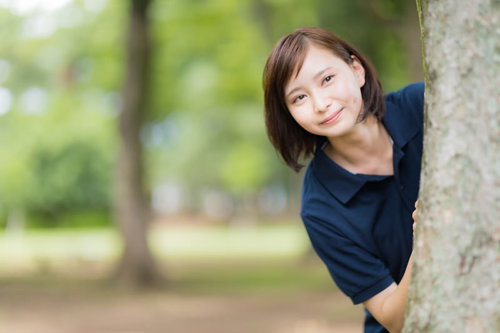 木陰から見守る介護士の女性 - 高齢者ケアの日常