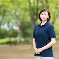 新緑の公園で笑顔を見せる介護士の女性の写真