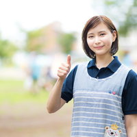 エプロン姿でいいねする女性（屋外）の写真