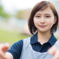 青いエプロンを着た介護士の女性が両手を差し伸べるの写真