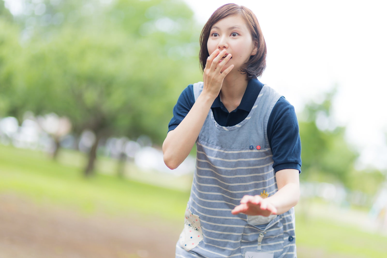 手で口元を押さえ驚いた表情を見せる介護士の女性［モデル：yumiko］