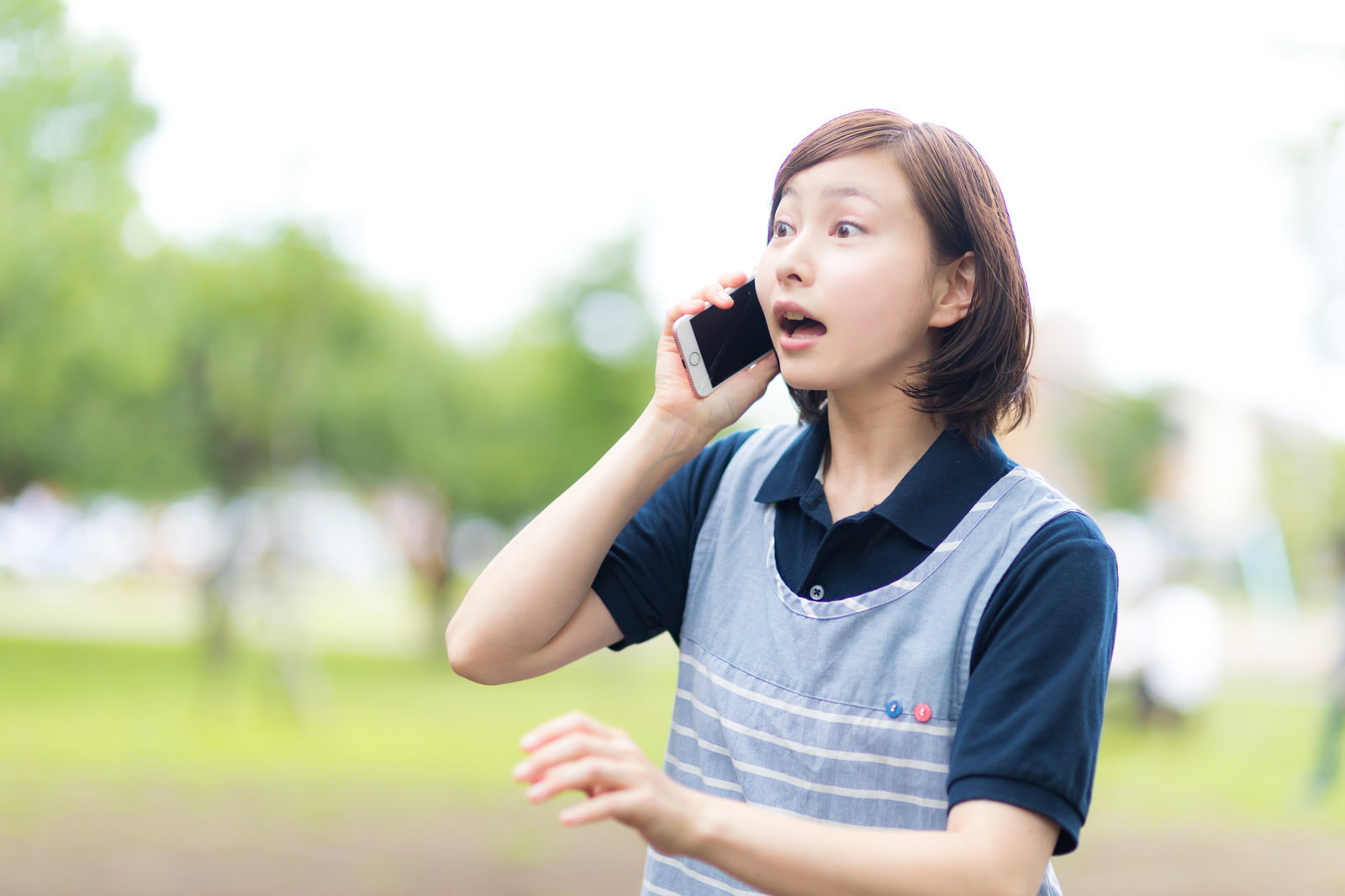 屋外でスマートフォンを使って通話している女性介護士［モデル：yumiko］
