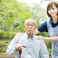公園で介護士さんと記念撮影する車椅子のお爺さんの写真
