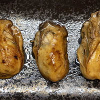 こんがりと焼けた牡蠣の剥き身、銀色の焼き台に並んだ海鮮食材の写真