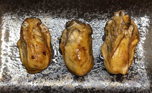 こんがりと焼けた牡蠣の剥き身、銀色の焼き台に並んだ海鮮食材
