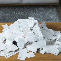 山盛りになった紙の領収書と経費管理・記帳業務の写真