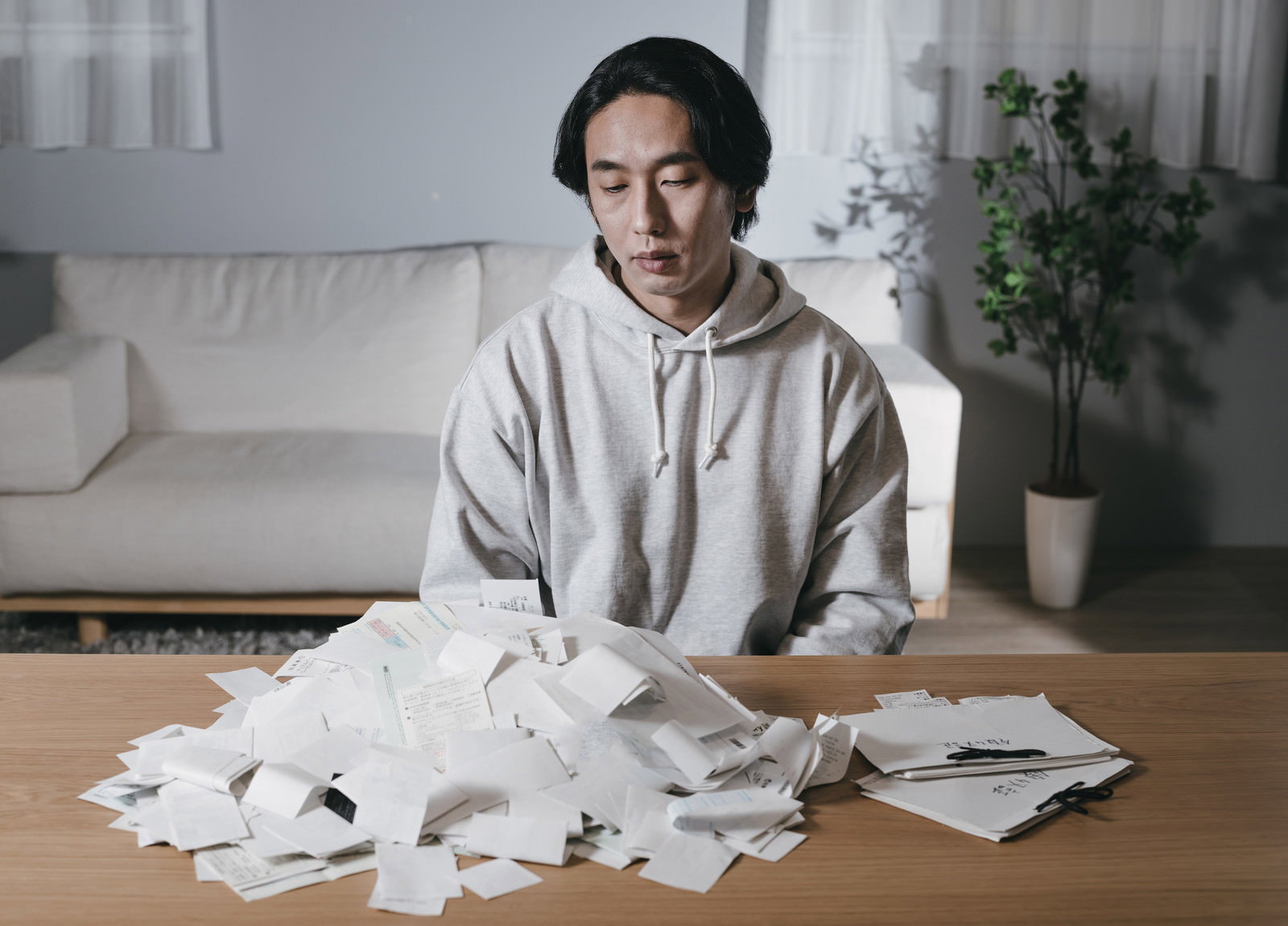 机の上の領収書を前に困った表情で頭を下げる男性［モデル：大川竜弥］
