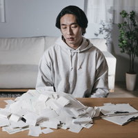 溜まりすぎた領収書に頭を抱える個人事業主の徹夜作業の写真