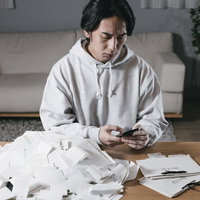 山積みの領収書に頭を抱える確定申告の男性の写真