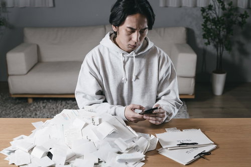 山積みの領収書に頭を抱える確定申告の男性