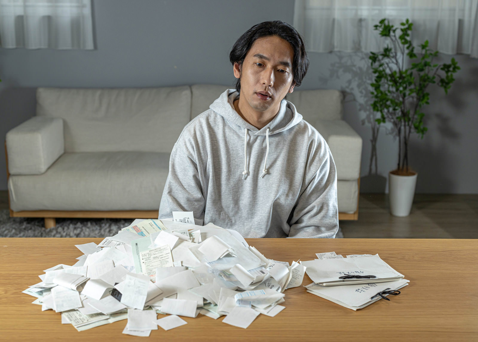 領収書に囲まれて困惑する男性［モデル：大川竜弥］