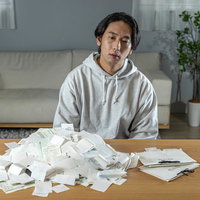 山盛りの領収書を前に呆然とする個人事業主男性の写真
