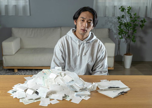 山盛りの領収書を前に呆然とする個人事業主男性