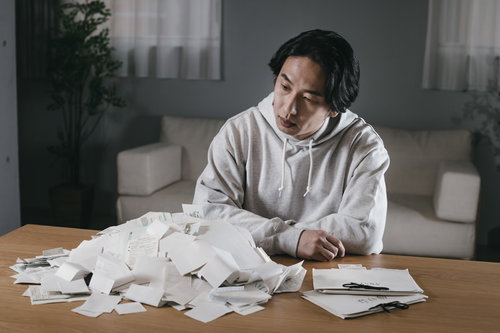 山積みの領収書に項垂れてしまう男性の確定申告