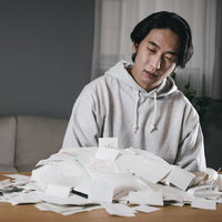 仕分けしてこなかった領収書の山に向き合う男性の写真