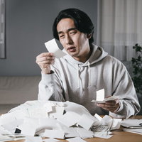 溜まった領収書の仕分けに苦悩する男性のデスクワークの写真