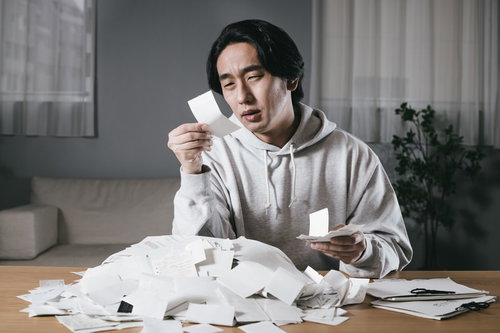 溜まった領収書の仕分けに苦悩する男性のデスクワーク