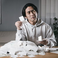 領収書を手に困惑した表情で眺める仕分け男子の写真