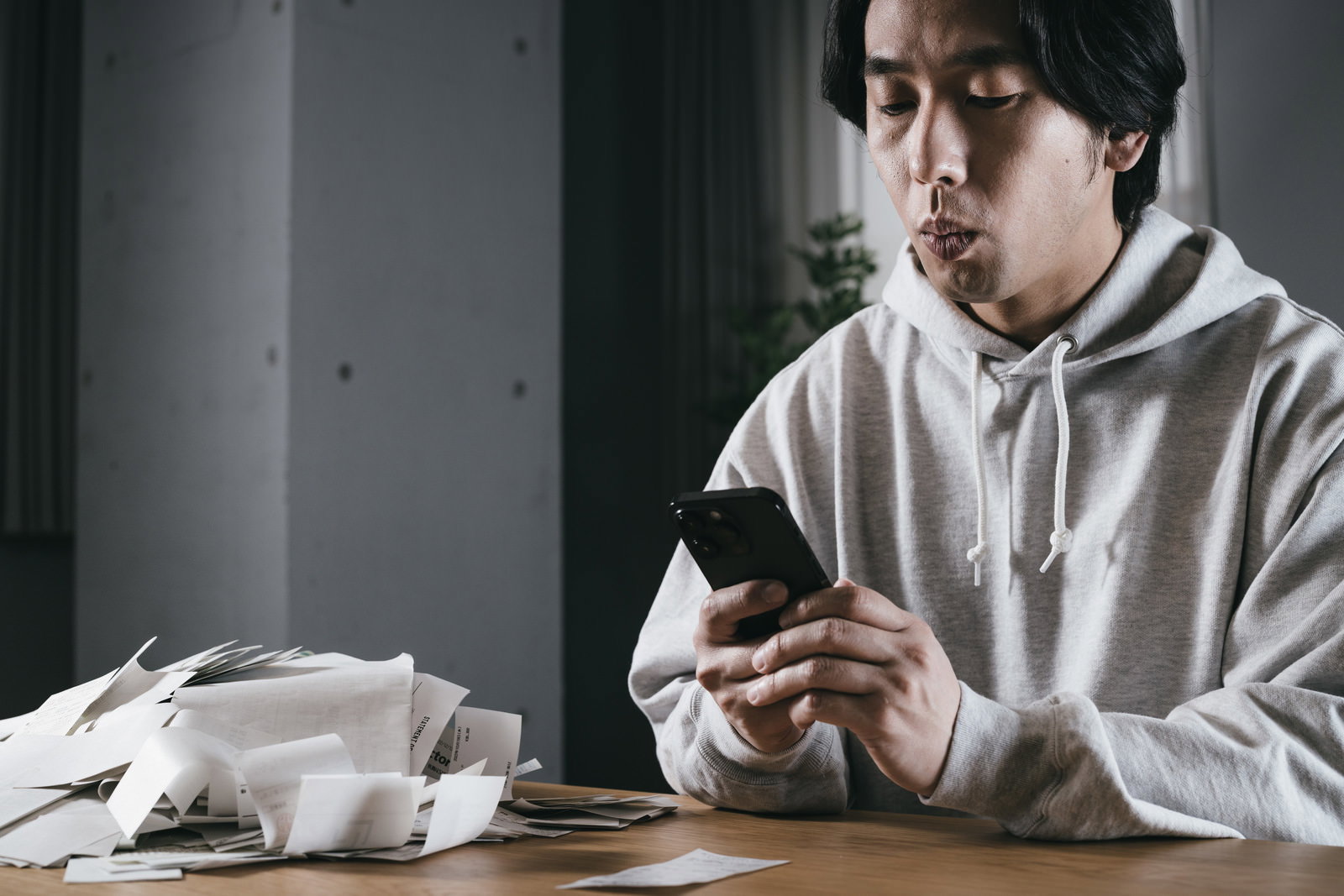 領収書を手にしてスマートフォンで撮影する男性［モデル：大川竜弥］
