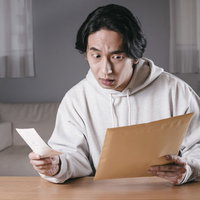 封筒を閉じた後、書類の入れ忘れが発覚した男性の写真