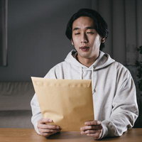 嫌な予感がする茶色い封書を受け取った男性の写真
