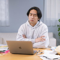 税理士のアドバイスに納得がいかず腕を組んで考える男性の写真