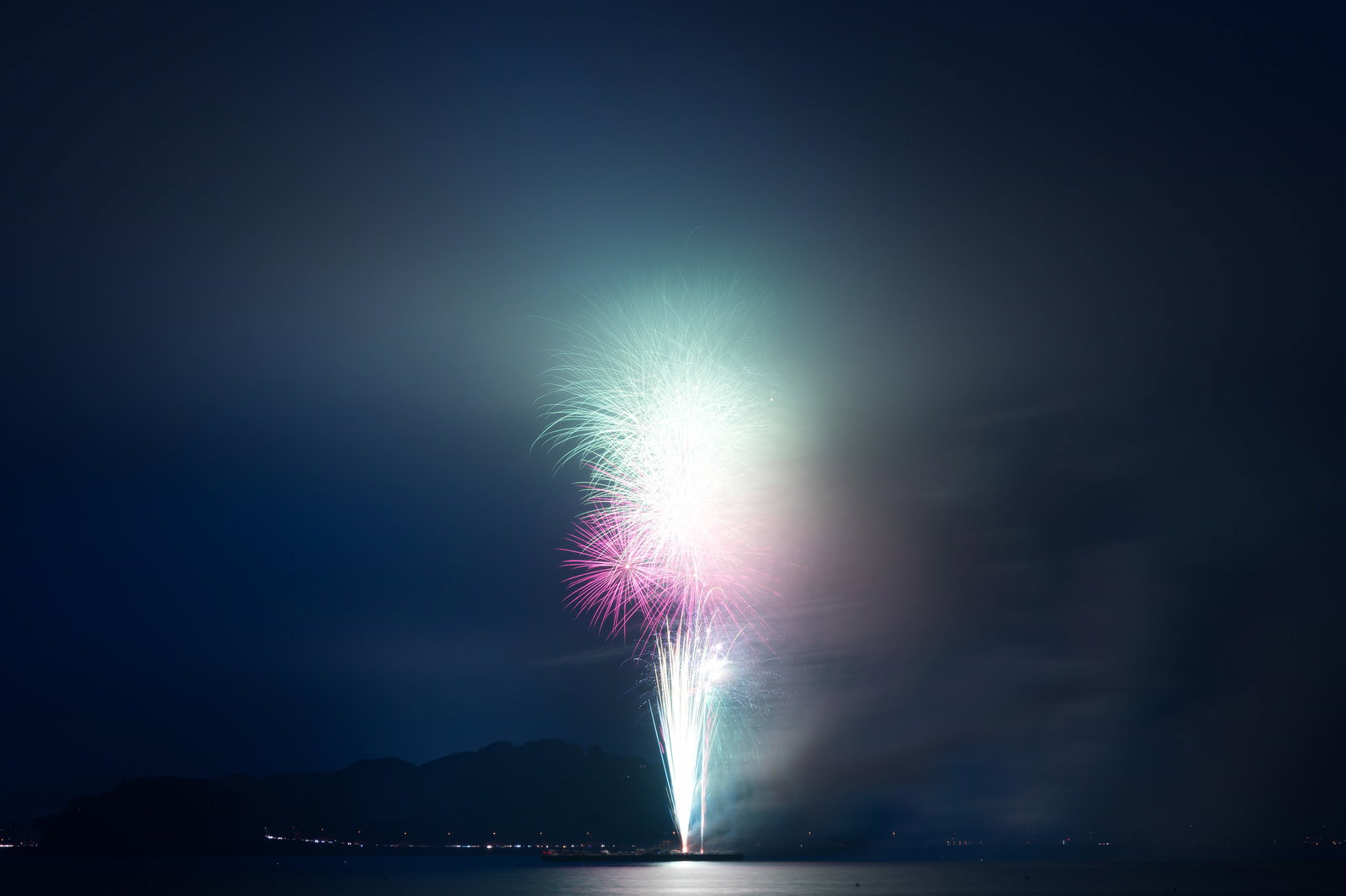 煙に包まれて光る花火大会の夜空