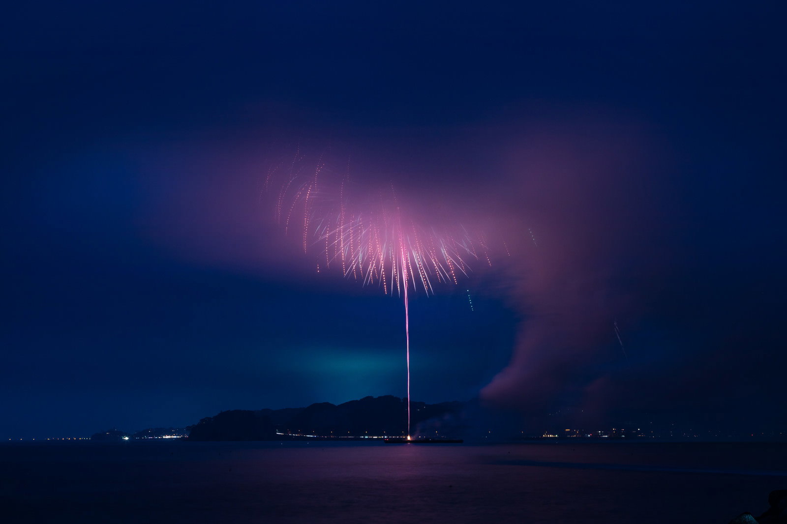 夜空に広がる煙で花火が見えにくくなっている様子