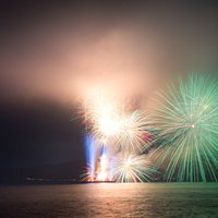 煙で光が霞む鎌倉花火大会のスターマインの写真