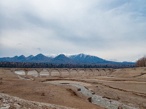 雪をかぶった山々を背景に水中に沈むタウシュベツ川橋梁