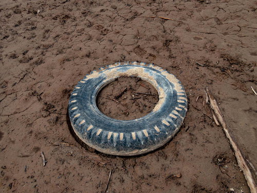泥の湖底に放置されたタイヤの写真